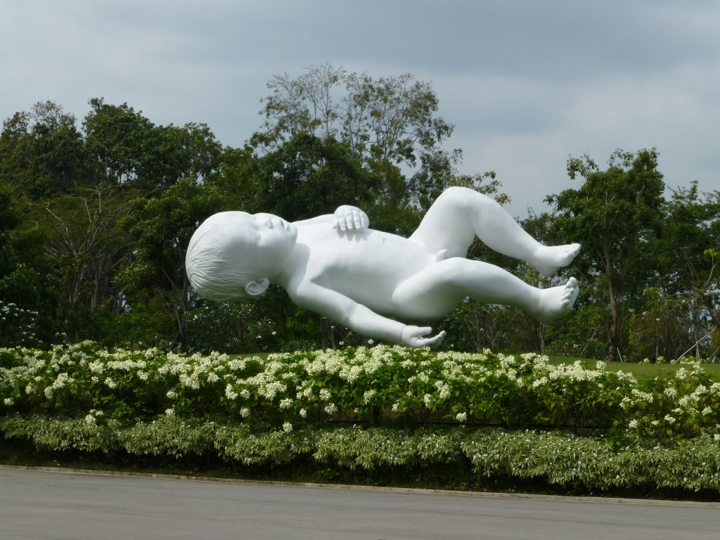 Скульптура ребенка в садах, парящая над клумбой
